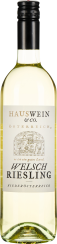 Eine Weinflasche mit hellem Etikett und schwarzem Verschluss. Im Vordergrund eine detaillierte Zeichnung einer ländlichen Szene. Der Wein hat eine klare, hellgelbe Farbe.